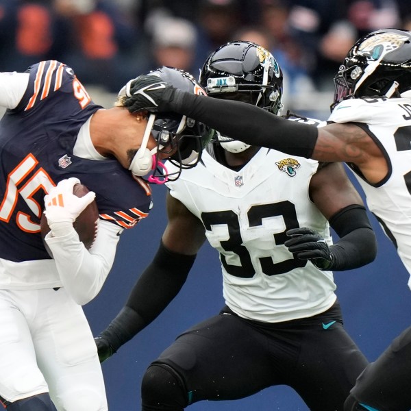 Chicago Bears wide receiver Rome Odunze (15) is tackled by Jacksonville Jaguars linebacker Devin Lloyd (33) and Jaguars safety Antonio Johnson (26) during an NFL football game at the Tottenham Hotspur stadium between the Jacksonville Jaguars and Chicago Bears in London, Sunday, Oct. 13, 2024. (AP Photo/Alastair Grant)