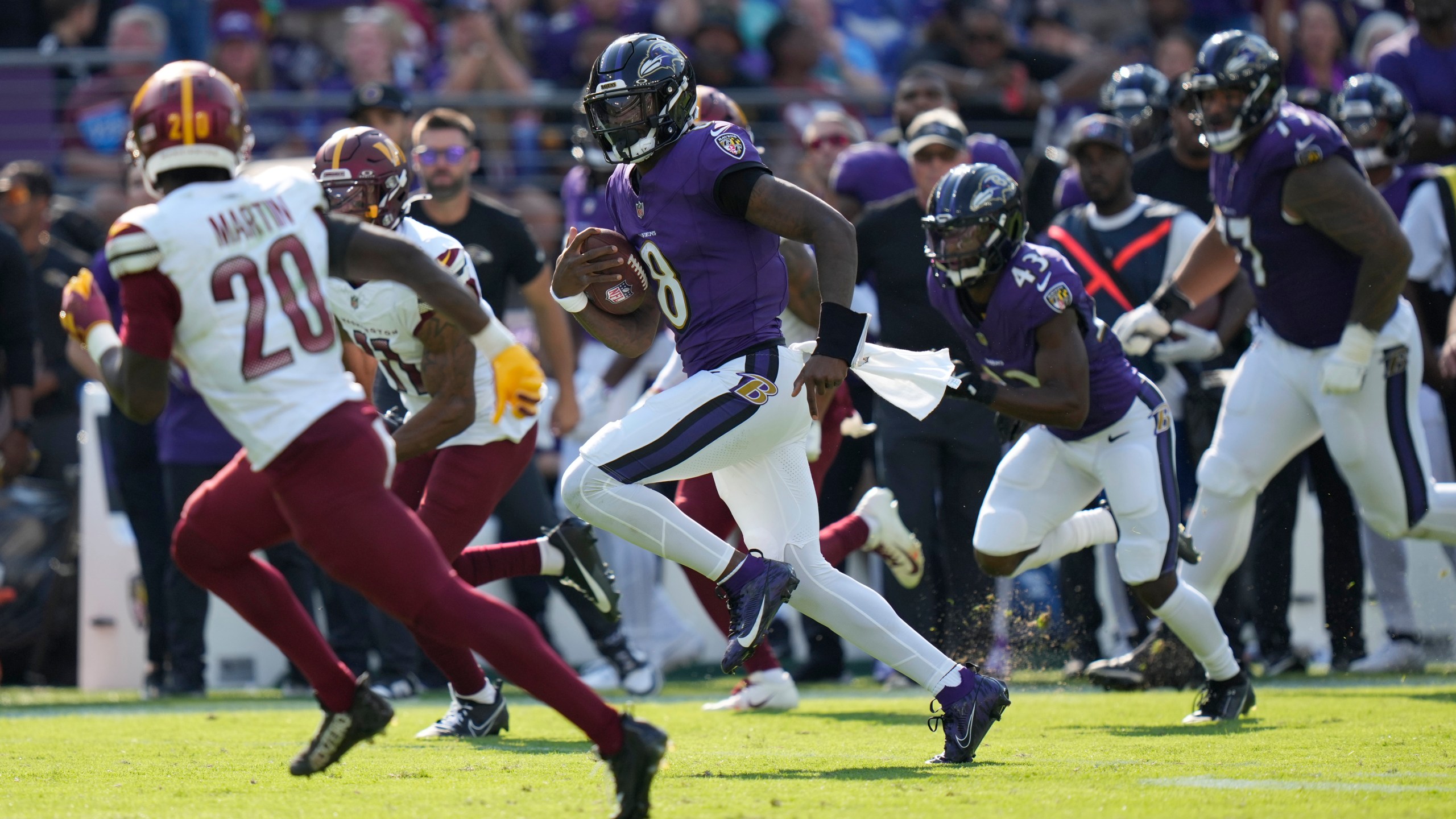 Baltimore Ravens quarterback Lamar Jackson (8) runs for a 33-yard gain as Washington Commanders safety Quan Martin (20) defends during the second half of an NFL football game Sunday, Oct. 13, 2024, in Baltimore. (AP Photo/Stephanie Scarbrough)