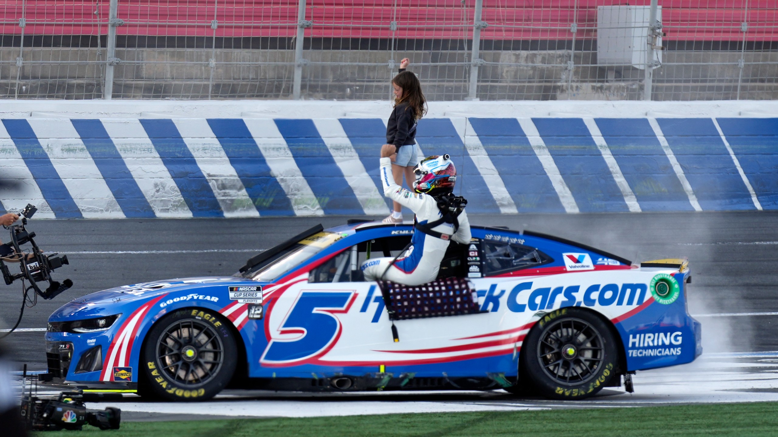 Kyle Larson celebrates with his daughter Audrey Larson, 6, top, after winning a NASCAR Cup Series auto race at Charlotte Motor Speedway in Concord, N.C., Sunday, Oct. 13, 2024. (AP Photo/Chuck Burton)