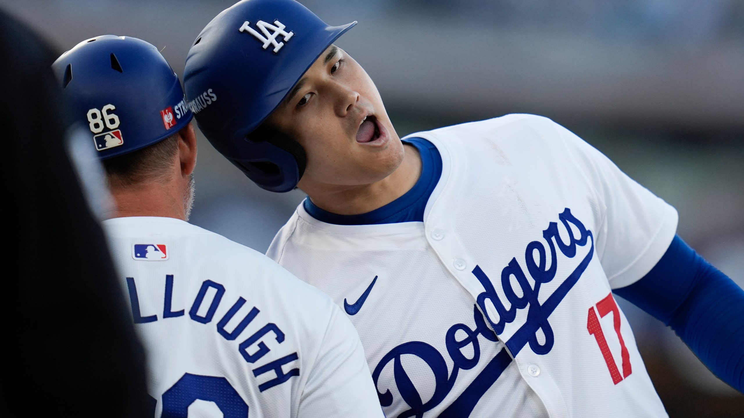 Los Angeles Dodgers' Shohei Ohtani, right, bumps heads with first base coach Clayton McCullough after his single against the New York Mets during the second inning in Game 1 of a baseball NL Championship Series, Sunday, Oct. 13, 2024, in Los Angeles. (AP Photo/Gregory Bull)