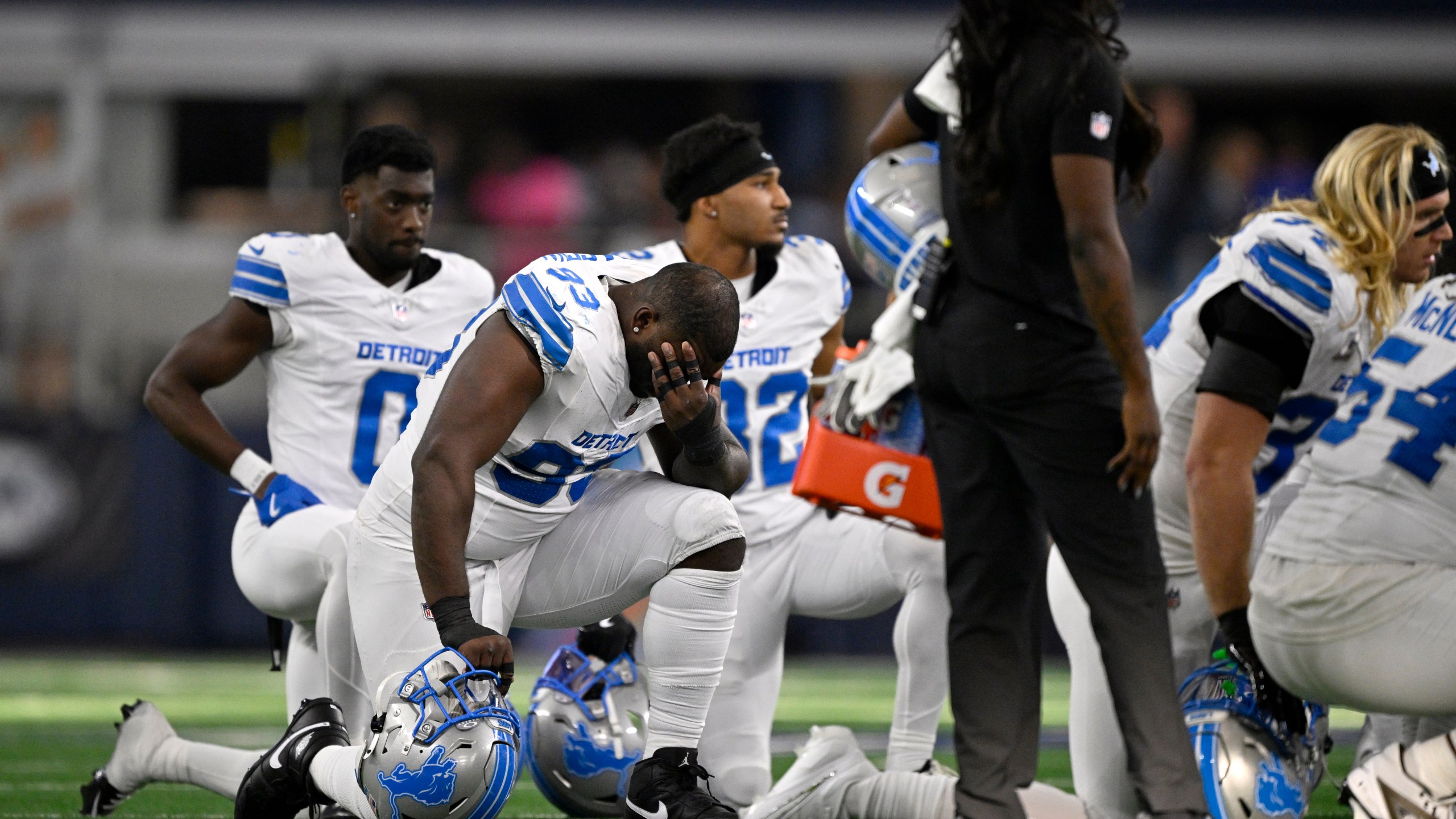 Detroit Lions players kneel on the field as Aidan Hutchinson, not pictured, is attended to by staff afer suffering an unkown injury second half of an NFL football game against the Dallas Cowboys in Arlington, Texas, Sunday, Oct. 13, 2024. (AP Photo/Jerome Miron)