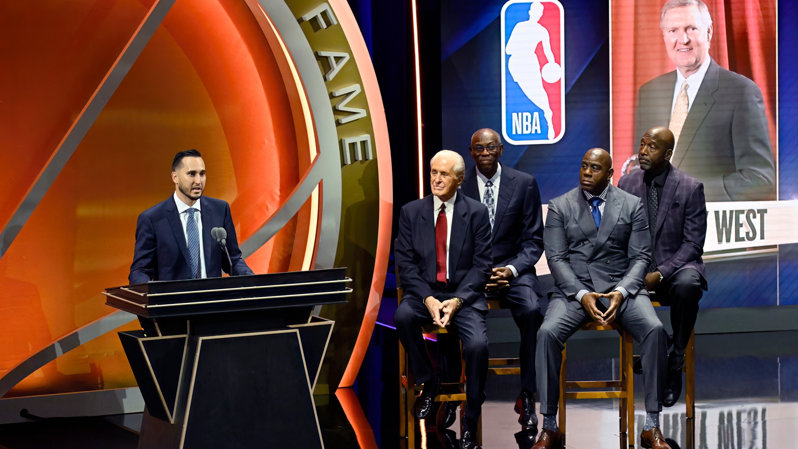 Jonnie West, left, speaks during his late father Jerry West's enshrinement in the Basketball Hall of Fame as, from second from left to right, Pat Riley, Bob McAdoo, Magic Johnson and James Worthy look on Sunday Oct. 13, 2024, in Springfield, Mass. (AP Photo/Jessica Hill)