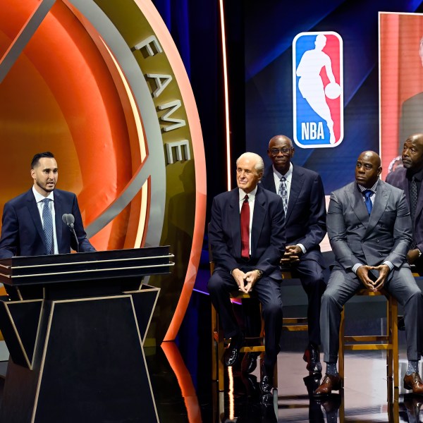 Jonnie West, left, speaks during his late father Jerry West's enshrinement in the Basketball Hall of Fame as, from second from left to right, Pat Riley, Bob McAdoo, Magic Johnson and James Worthy look on Sunday Oct. 13, 2024, in Springfield, Mass. (AP Photo/Jessica Hill)