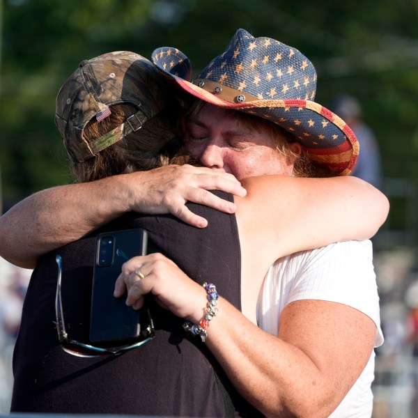 FILE - People hug after Republican presidential candidate former President Donald Trump was helped off the stage at a campaign event in Butler, Pa., July 13, 2024. (AP Photo/Gene J. Puskar, File)