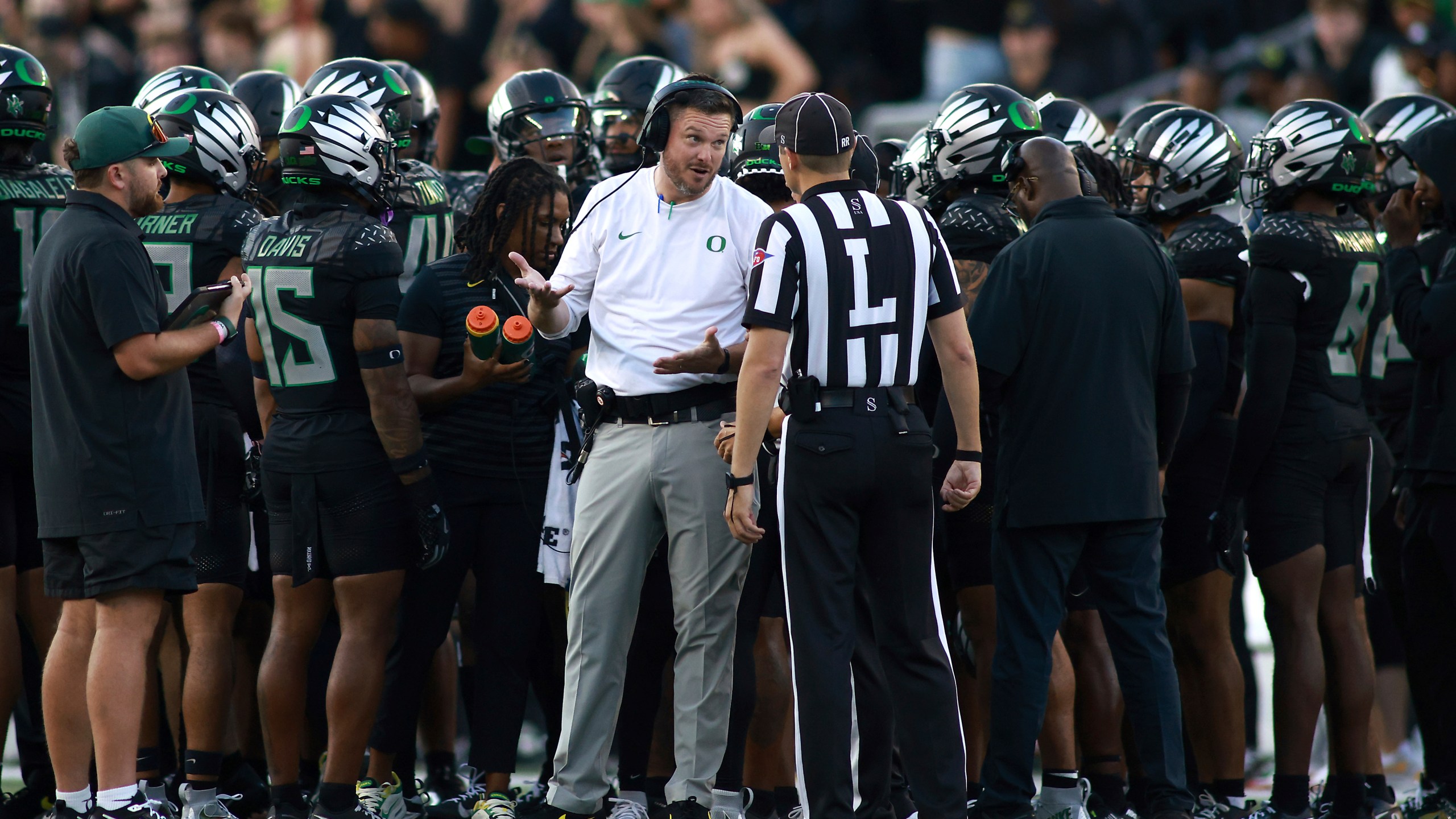 Oregon head coach Dan Lanning, center left, talks with a referee, center right, during an NCAA college football game against Ohio State, Saturday, Oct. 12, 2024, in Eugene, Ore. (AP Photo/Lydia Ely)