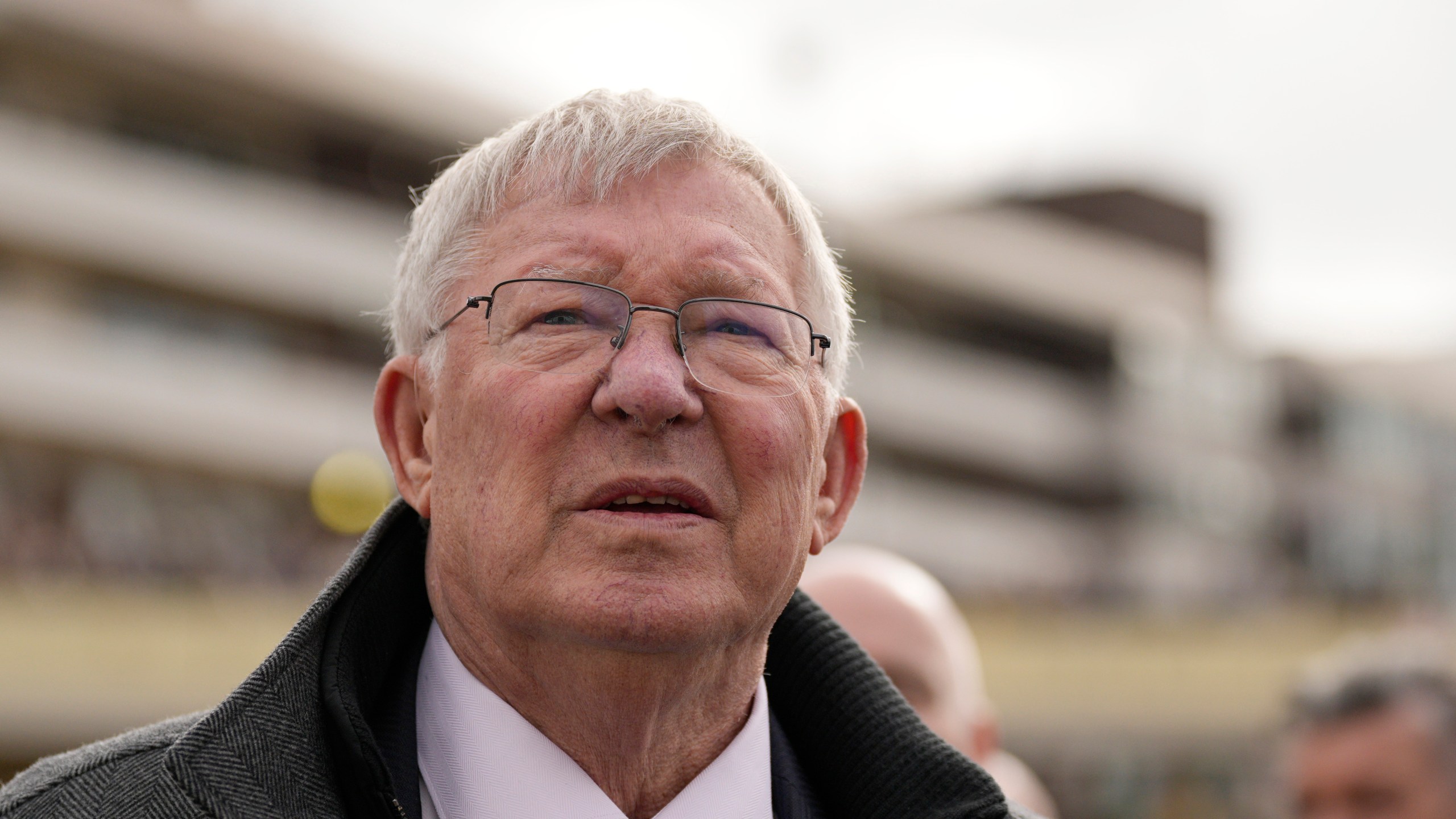 FILE - Former Manchester United manager Alex Ferguson, watches a large TV screen during The County Hurdle race as his horse L'Eau Du Sud came in second place behind Absurde, during the final day of the Cheltenham Festival at Cheltenham Racecourse, England, Friday, March 15, 2024. (AP Photo/Dave Shopland, File)