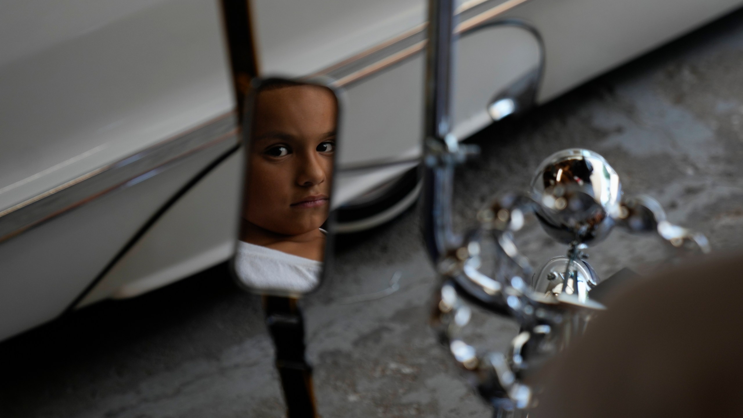 Daniel Marquez, 8, is reflected in the mirror of his chrome lowrider bike, built by himself and family friends in memory of his late father Alberto, a longtime member of lowrider car clubs, Saturday, Sept. 14, 2024, at his home in Frankfort, Ill. (AP Photo/Erin Hooley)