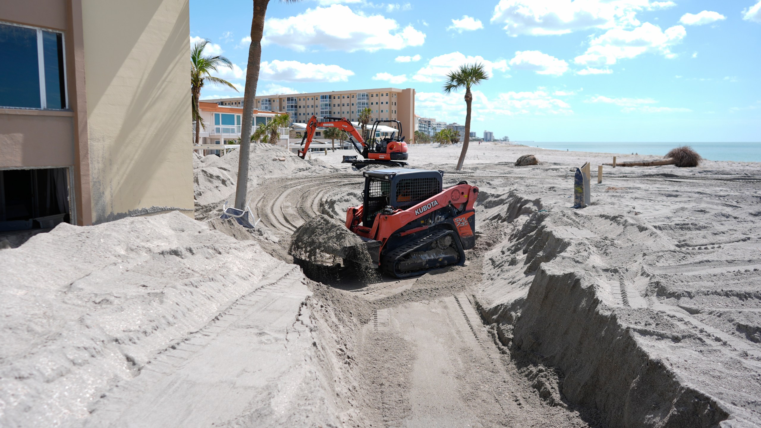 Scott Bennett, a contractor who specializes in storm recovery, uses a skid steer to remove sand around 5 feet deep from the patio of a beachfront condominium in Venice, Fla., following the passage of Hurricane Milton, Saturday, Oct. 12, 2024. (AP Photo/Rebecca Blackwell)