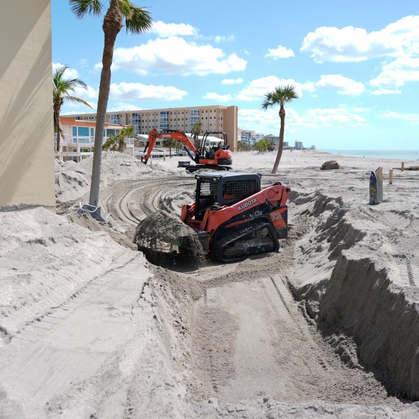 Scott Bennett, a contractor who specializes in storm recovery, uses a skid steer to remove sand around 5 feet deep from the patio of a beachfront condominium in Venice, Fla., following the passage of Hurricane Milton, Saturday, Oct. 12, 2024. (AP Photo/Rebecca Blackwell)