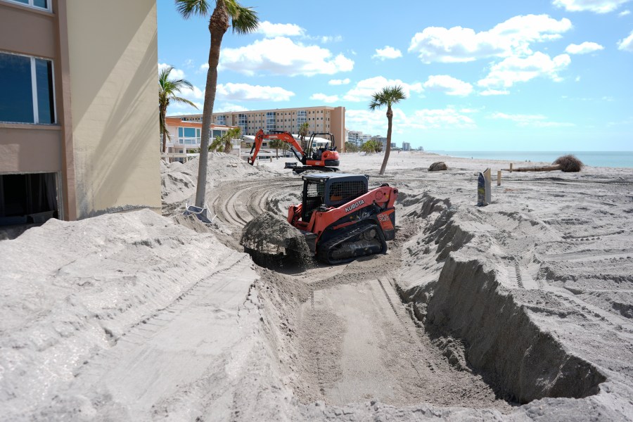 Scott Bennett, a contractor who specializes in storm recovery, uses a skid steer to remove sand around 5 feet deep from the patio of a beachfront condominium in Venice, Fla., following the passage of Hurricane Milton, Saturday, Oct. 12, 2024. (AP Photo/Rebecca Blackwell)