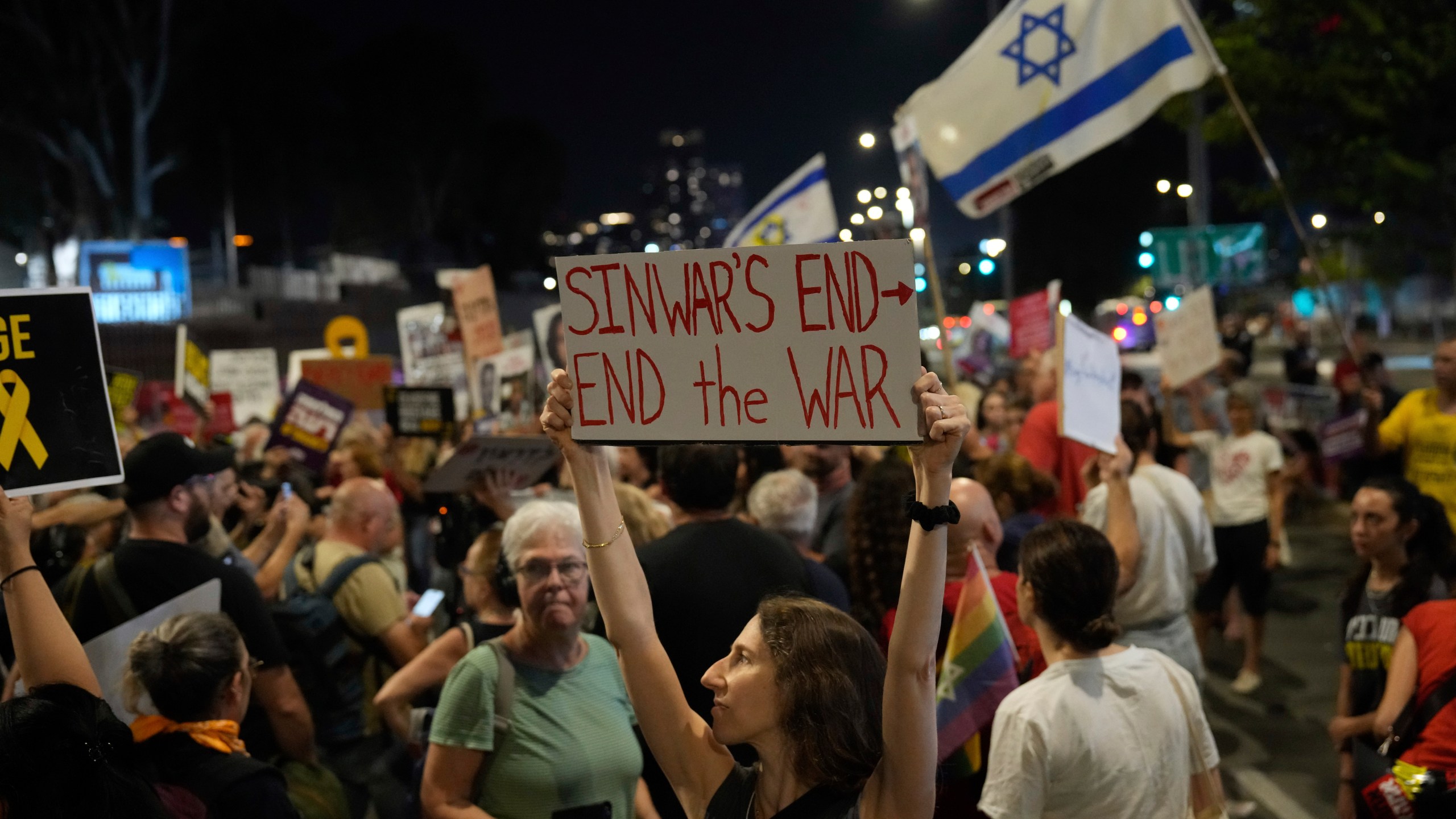 A demonstrator holds a sign about the killing of Hamas leader Yahya Sinwar during a protest calling for a cease-fire deal and the immediate release of hostages held by Hamas on Thursday, Oct. 17, 2024, in Tel Aviv, Israel. (AP Photo/Ariel Schalit)