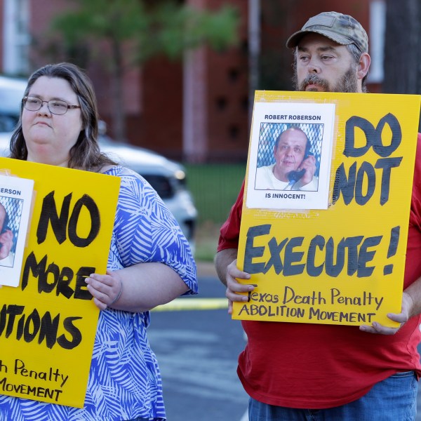 Jennifer Martin, left, and Thomas Roberson, older brother of condemned prisoner Robert Roberson, right, holds signs as they protest outside the prison where Roberson is scheduled for execution at the Huntsville Unit of the Texas State Penitentiary, Thursday, Oct. 17, 2024, in Huntsville, Texas. (AP Photo/Michael Wyke)