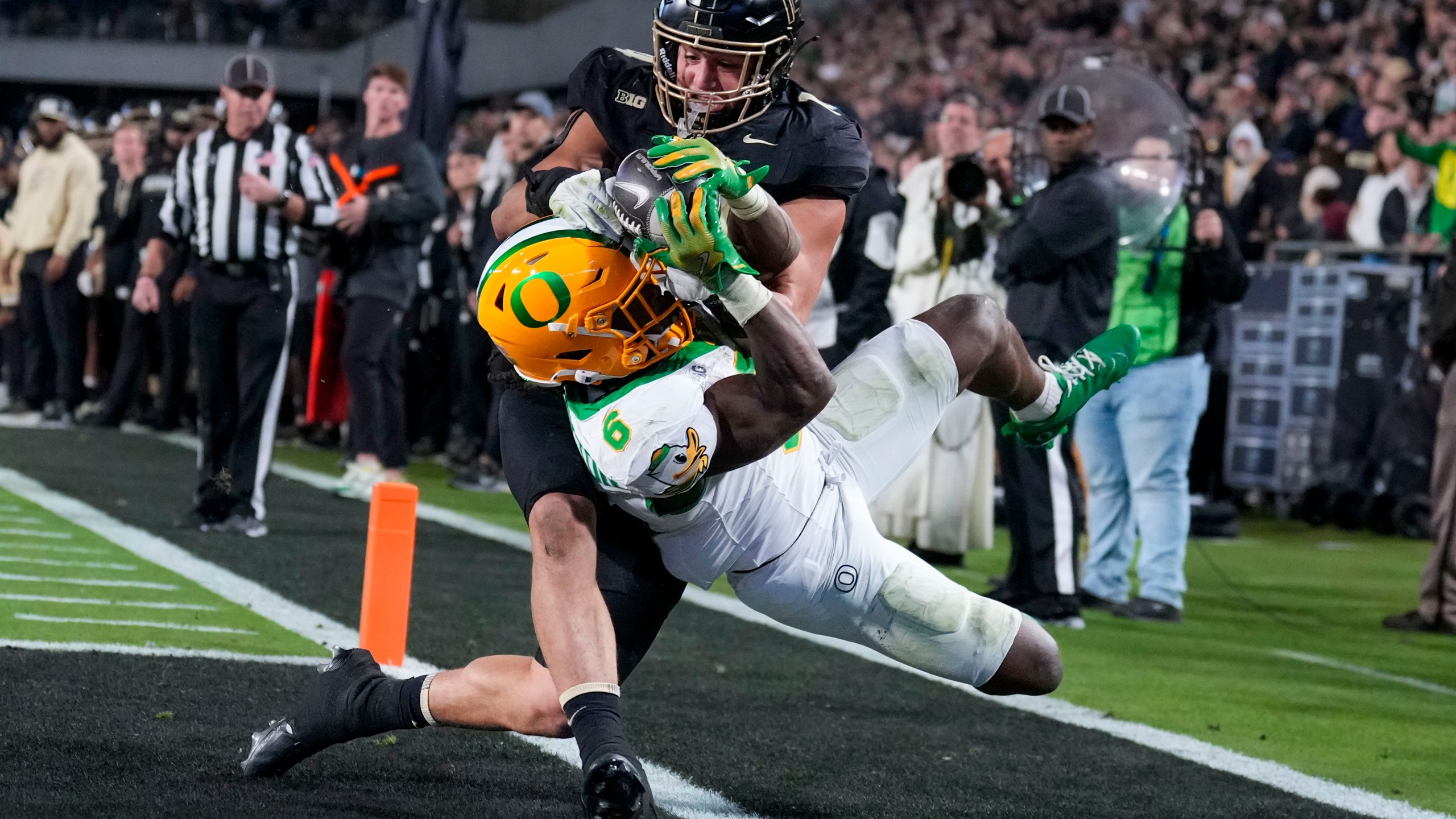 Oregon running back Noah Whittington (6) is forced out of bounds by of Purdue linebacker Yanni Karlaftis, top, after scoring a touchdown during the second half of an NCAA college football game in West Lafayette, Ind., Friday, Oct. 18, 2024. (AP Photo/AJ Mast)