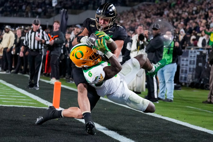 Oregon running back Noah Whittington (6) is forced out of bounds by of Purdue linebacker Yanni Karlaftis, top, after scoring a touchdown during the second half of an NCAA college football game in West Lafayette, Ind., Friday, Oct. 18, 2024. (AP Photo/AJ Mast)