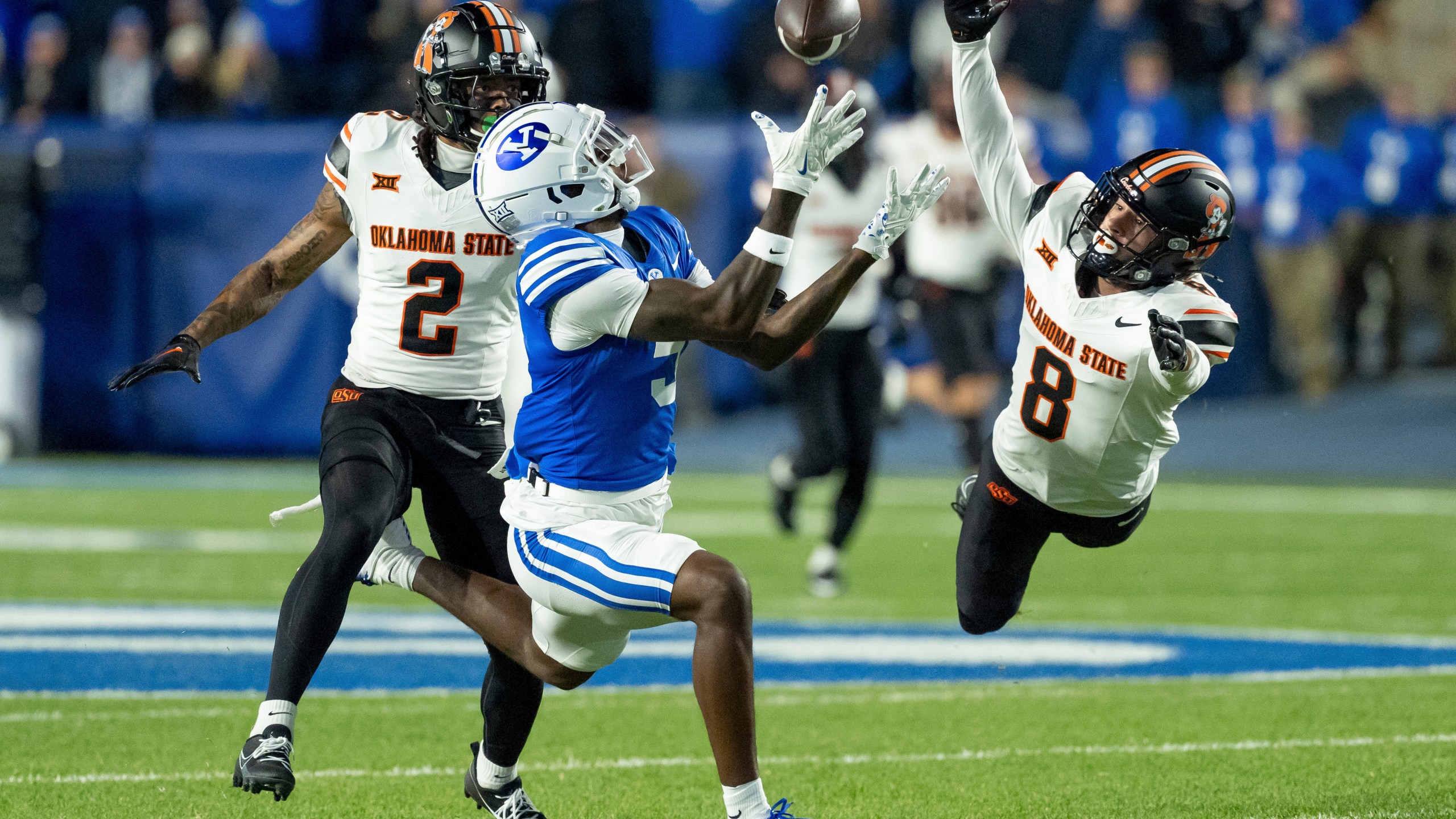 BYU wide receiver Darius Lassiter makes a catch ahead of Oklahoma State cornerback Korie Black (2) and safety Parker Robertson (8) in the first half of an NCAA college football game, Friday, Oct. 18, 2024, in Provo, Utah. (AP Photo/Spenser Heaps)