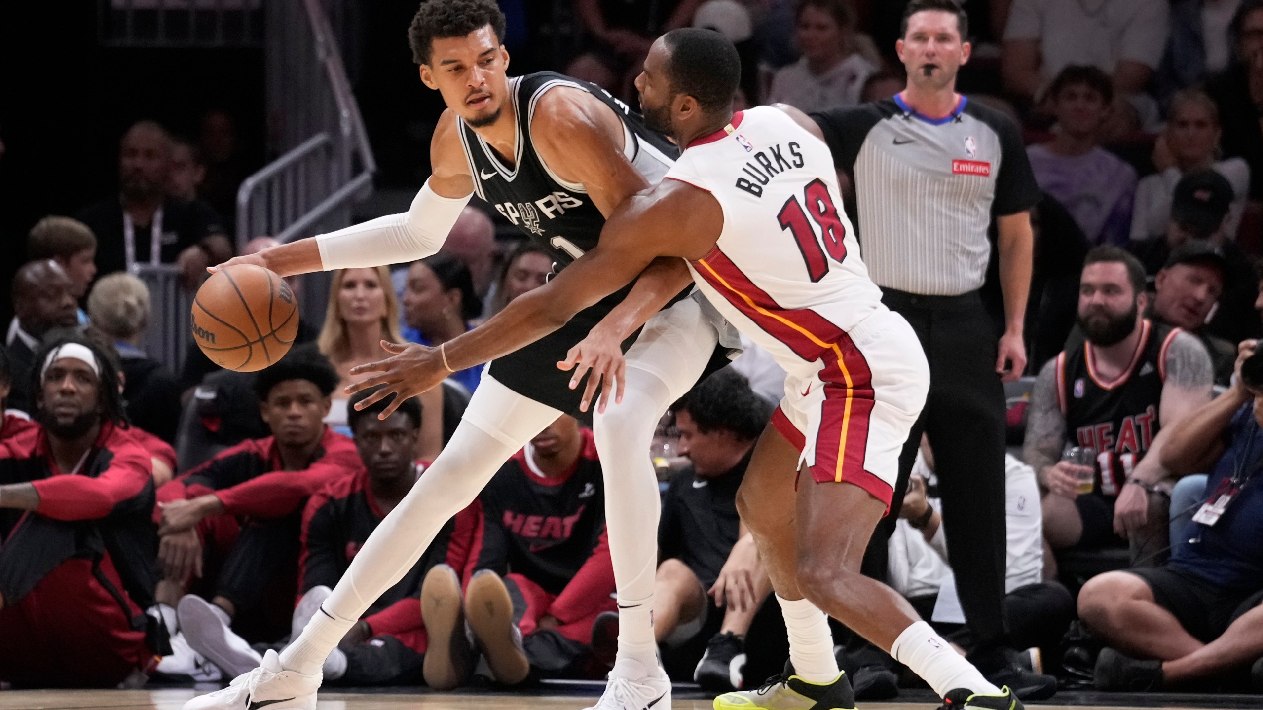 San Antonio Spurs forward Victor Wembanyama (1) drives up against Miami Heat guard Alec Burks (18) during the first half of an NBA preseason basketball game, Tuesday, Oct. 15, 2024, in Miami. (AP Photo/Wilfredo Lee)