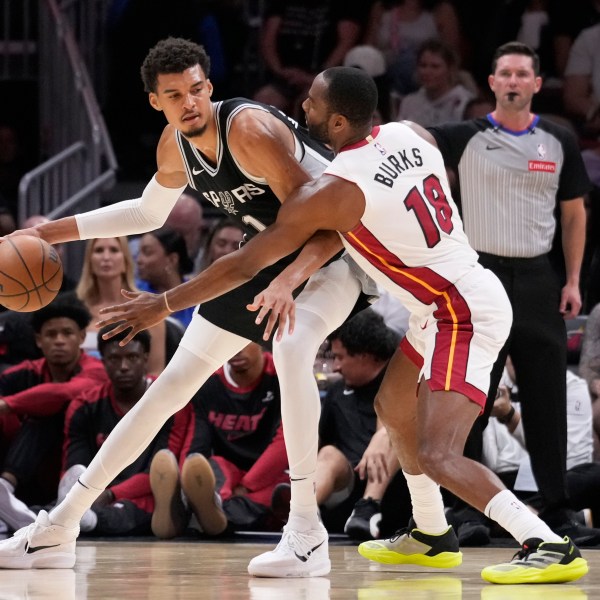 San Antonio Spurs forward Victor Wembanyama (1) drives up against Miami Heat guard Alec Burks (18) during the first half of an NBA preseason basketball game, Tuesday, Oct. 15, 2024, in Miami. (AP Photo/Wilfredo Lee)