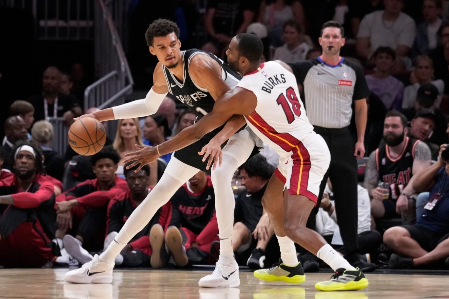 San Antonio Spurs forward Victor Wembanyama (1) drives up against Miami Heat guard Alec Burks (18) during the first half of an NBA preseason basketball game, Tuesday, Oct. 15, 2024, in Miami. (AP Photo/Wilfredo Lee)