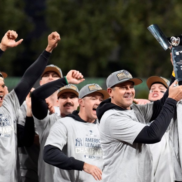 New York Yankees manager Aaron Boone holds up the American League Championship trophy after Game 5 of the baseball AL Championship Series against the Cleveland Guardians Sunday, Oct. 20, 2024, in Cleveland. The Yankees won 5-2 to advance to the World Series. (AP Photo/Sue Ogrocki)