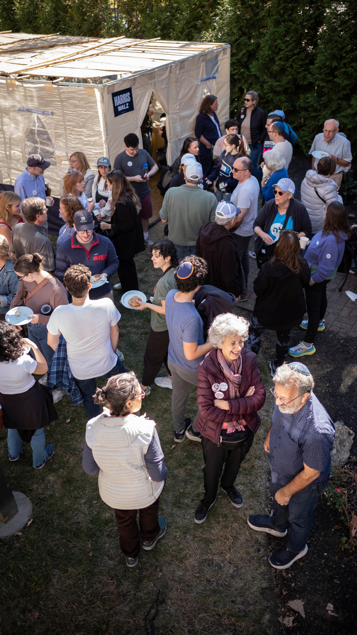 Supporters of Democratic presidential nominee Vice President Kamala Harris gather around a Sukkot before going door to door canvassing Jewish voters during the Jewish holiday in Bala Cynwyd, Pa, Sunday, Oct. 20, 2024. (AP Photo/Laurence Kesterson)