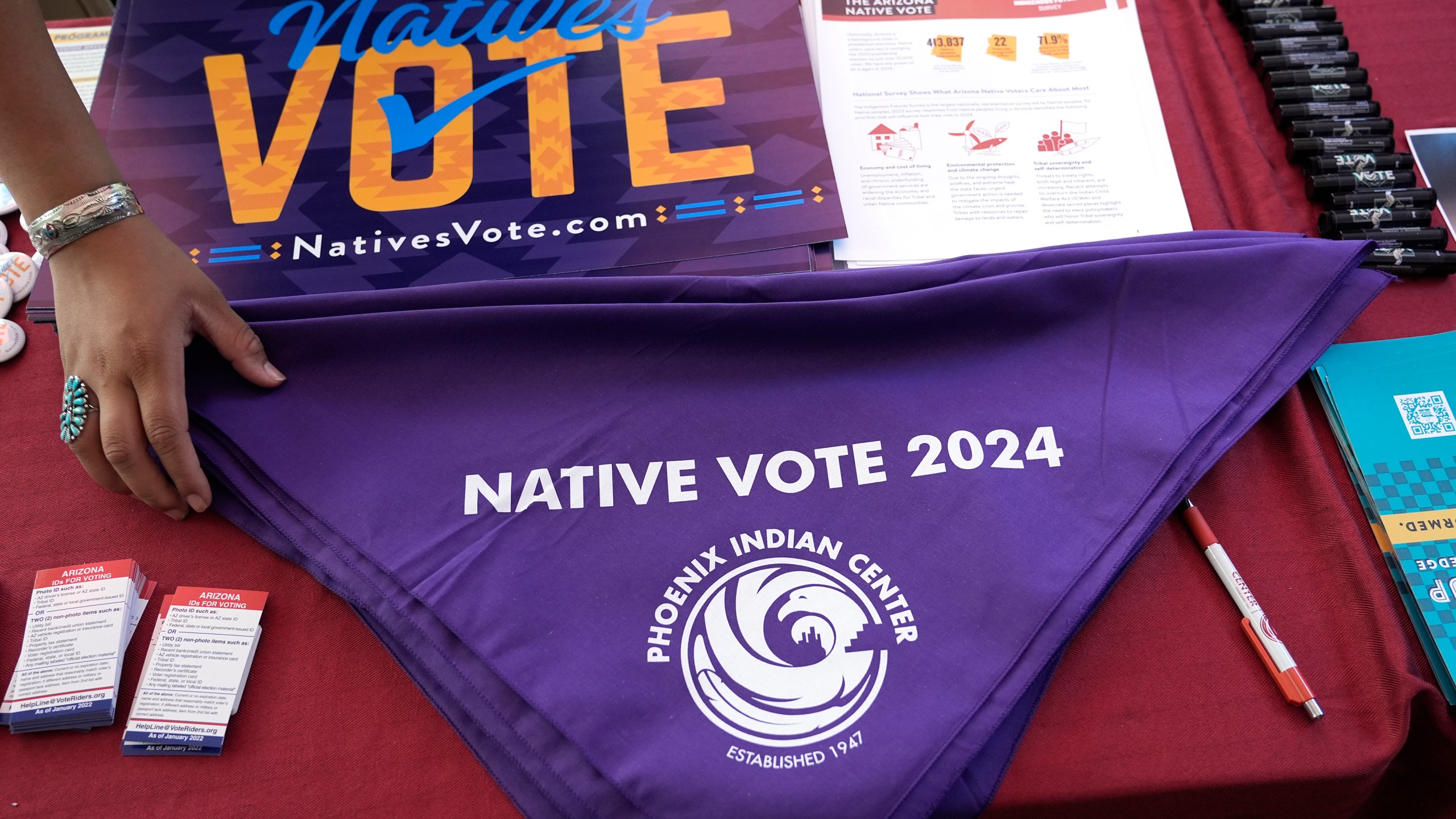 Voter information is on display at a Phoenix Indian Center booth during an Indigenous Peoples' Day event, Monday, Oct. 14, 2024, in Phoenix. (AP Photo/Ross D. Franklin)