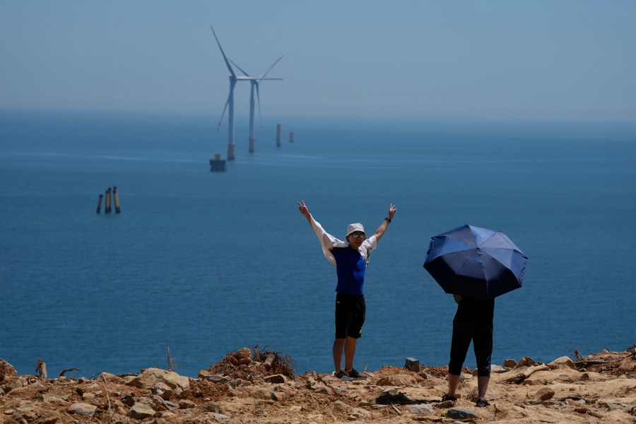 FILE - A tourist poses for photos near turbines along the Taiwan Straits in Pingtan in eastern China's Fujian province, on Aug. 6, 2022. (AP Photo/Ng Han Guan, File)