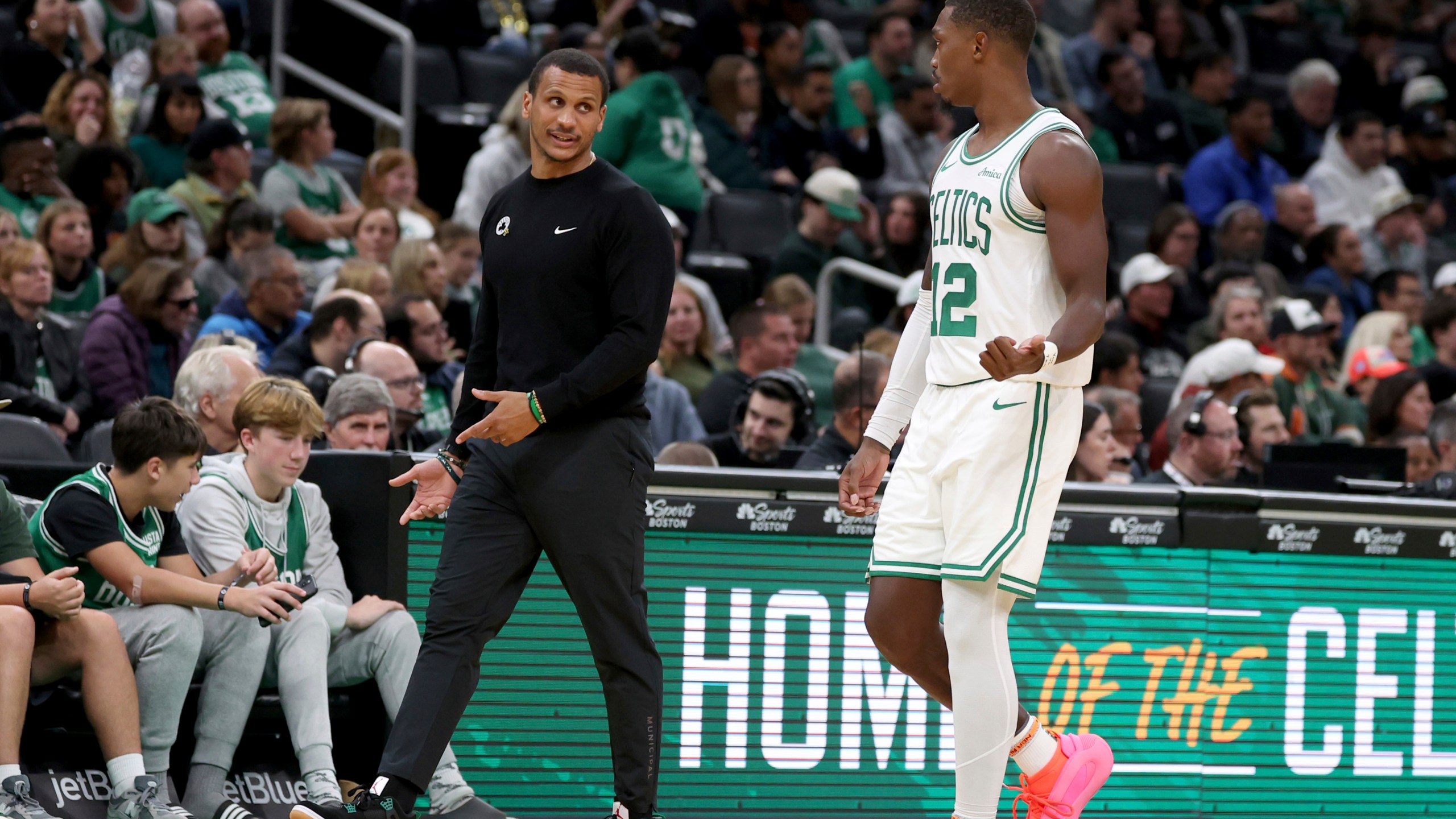 Boston Celtics head coach Joe Mazzulla, front left, speaks with Boston Celtics guard Lonnie Walker IV (12) who walks to the team bench during the second half of a preseason NBA basketball game against the Toronto Raptors, Sunday, Oct. 13, 2024, in Boston. (AP Photo/Mark Stockwell)