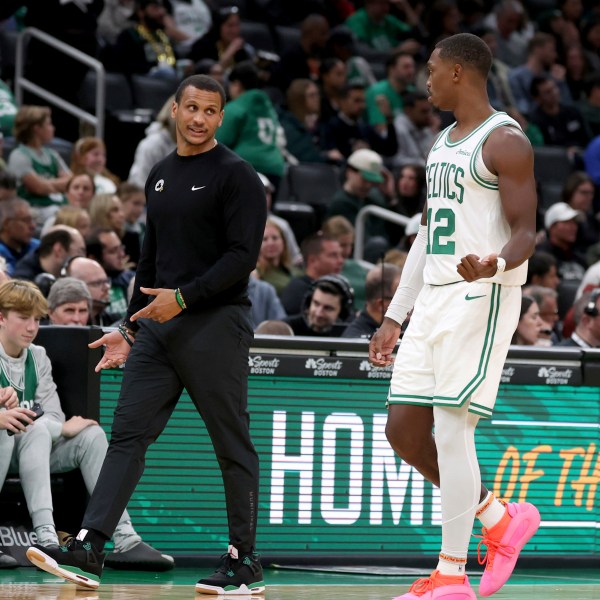 Boston Celtics head coach Joe Mazzulla, front left, speaks with Boston Celtics guard Lonnie Walker IV (12) who walks to the team bench during the second half of a preseason NBA basketball game against the Toronto Raptors, Sunday, Oct. 13, 2024, in Boston. (AP Photo/Mark Stockwell)