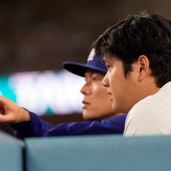 Los Angeles Dodgers' Shohei Ohtani and pitcher Yoshinobu Yamamoto watch during the sixth inning in Game 6 of a baseball NL Championship Series against the New York Mets, Sunday, Oct. 20, 2024, in Los Angeles. (AP Photo/Ashley Landis)