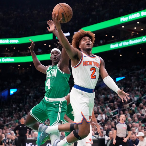 New York Knicks guard Miles McBride (2) drives to the basket past Boston Celtics guard Jrue Holiday (4) during the first half of an NBA basketball game, Tuesday, Oct. 22, 2024, in Boston. (AP Photo/Charles Krupa)