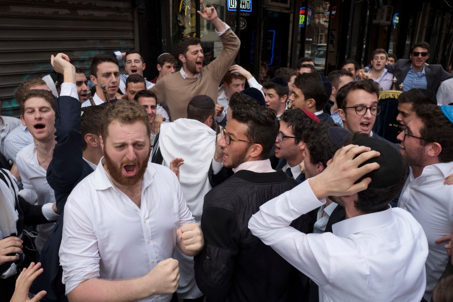 FILE - Jewish men celebrate Simchat Torah on a New York street, Friday, Oct. 13, 2017. The holiday marks the conclusion of the annual cycle of public Torah readings. (AP Photo/Mark Lennihan, File)