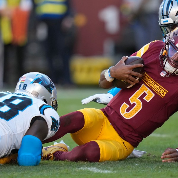 Washington Commanders quarterback Jayden Daniels (5) is tackled by Carolina Panthers linebacker Thomas Incoom (48) during the first half of an NFL football game, Sunday, Oct. 20, 2024, in Landover, Md. (AP Photo/Stephanie Scarbrough)