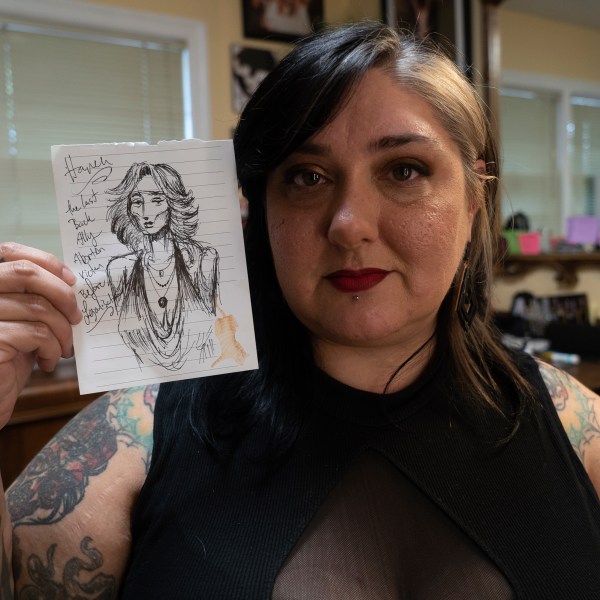 Tattoo artist Liz "Gruesome" Haycraft poses with a drawing of a fictitious back-alley abortion victim at her Breathless Arts Tattoo studio in Fayetteville, N.C., on Monday, Sept. 30, 2024. Haycraft drew it the day the U.S. Supreme Court overturned Roe v. Wade, which had previously legalized abortion nationwide. (AP Photo/Allen G. Breed)