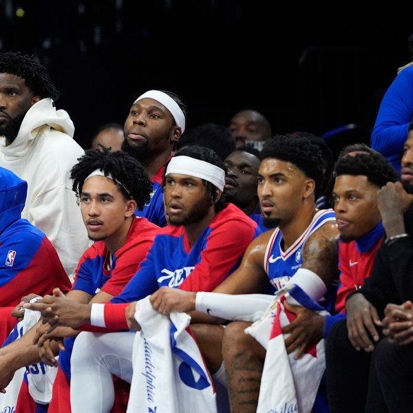 Philadelphia 76ers' Joel Embiid, top left, and Paul George, bottom right, watch from the bench during the first half of an NBA basketball game against the Milwaukee Bucks, Wednesday, Oct. 23, 2024, in Philadelphia. (AP Photo/Matt Slocum)