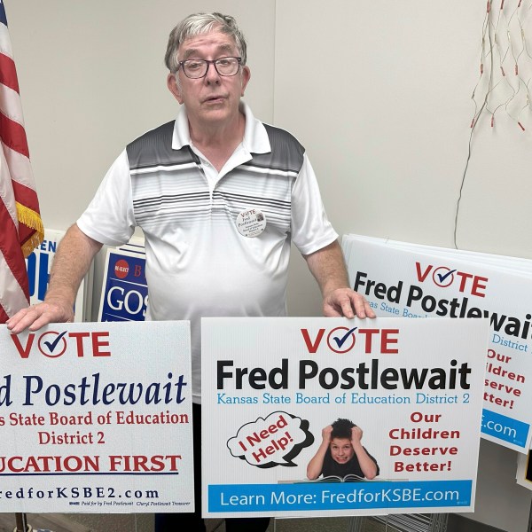 Fred Postlewait, a Republican candidate for the Kansas State Board of Education from Kansas City, Kan., shows off two of the yard signs available for supporters at the Republican Party's local headquarters in Johnson County, Tuesday, Oct. 1, 2024, in Overland Park, Kan. (AP Photo/John Hanna)