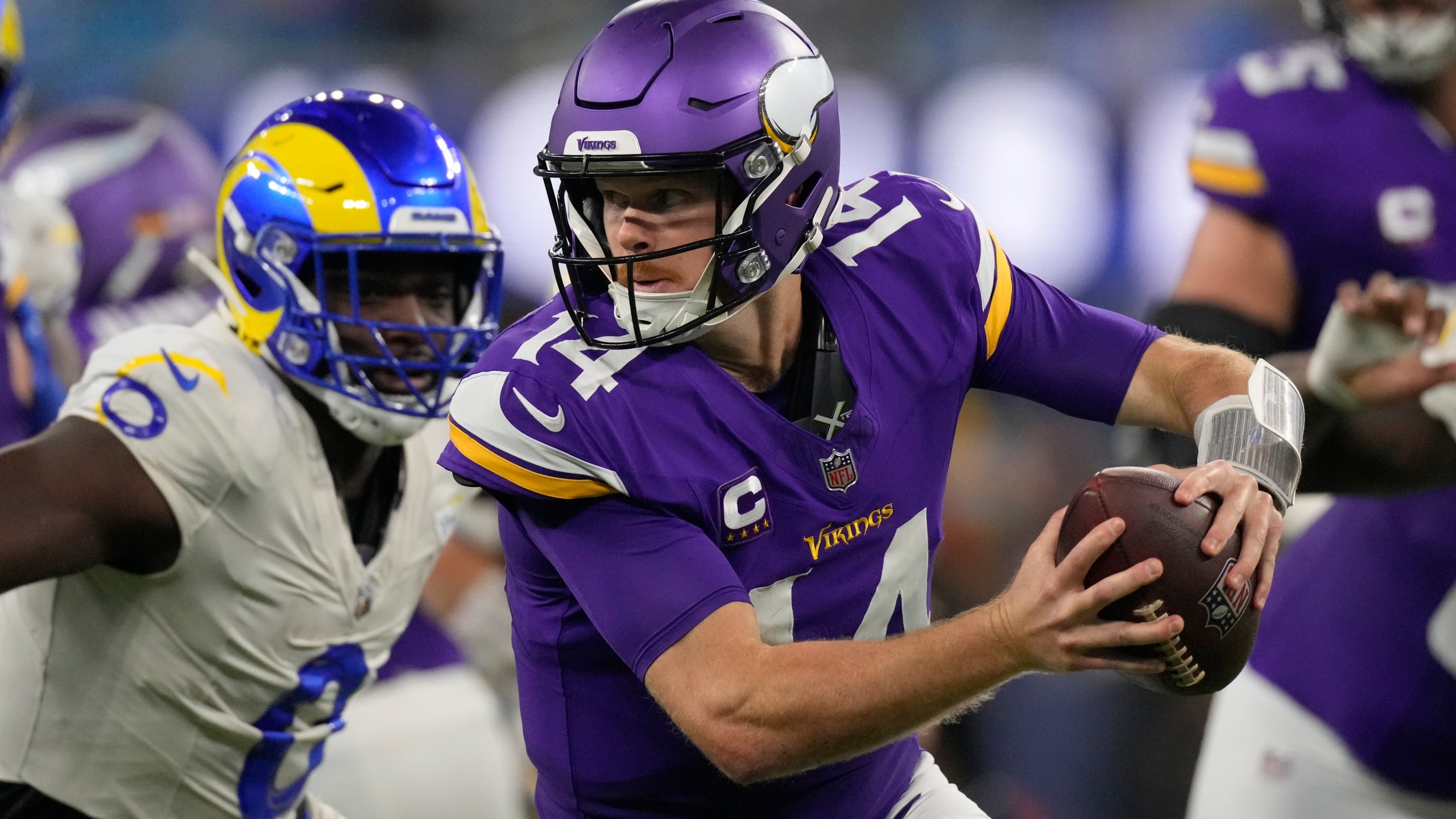 Minnesota Vikings quarterback Sam Darnold (14) scrambles while pressured by Los Angeles Rams linebacker Byron Young (0) during the first half of an NFL football game Thursday, Oct. 24, 2024, in Inglewood, Calif. (AP Photo/Mark J. Terrill)