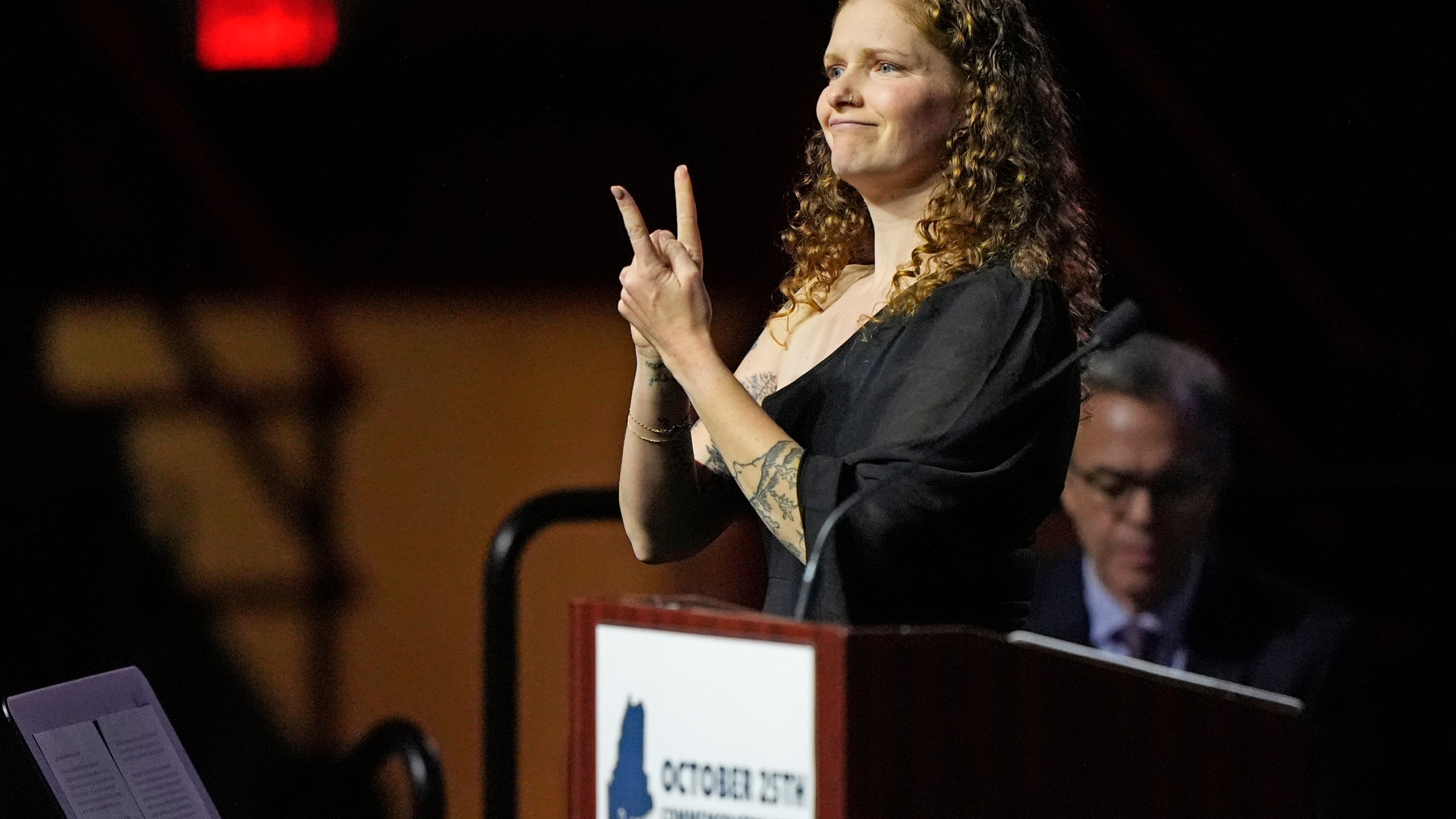 Elizabeth Seal, the wife of Joshua Seal, one of the four deaf victims in the Lewiston, Maine mass shooting, uses sign language as she addresses a commemoration event to mark the one year anniversary of the mass shooting in Lewiston, Maine, Friday, Oct. 25, 2024. (AP Photo/Robert F. Bukaty)