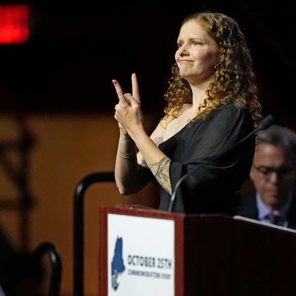 Elizabeth Seal, the wife of Joshua Seal, one of the four deaf victims in the Lewiston, Maine mass shooting, uses sign language as she addresses a commemoration event to mark the one year anniversary of the mass shooting in Lewiston, Maine, Friday, Oct. 25, 2024. (AP Photo/Robert F. Bukaty)