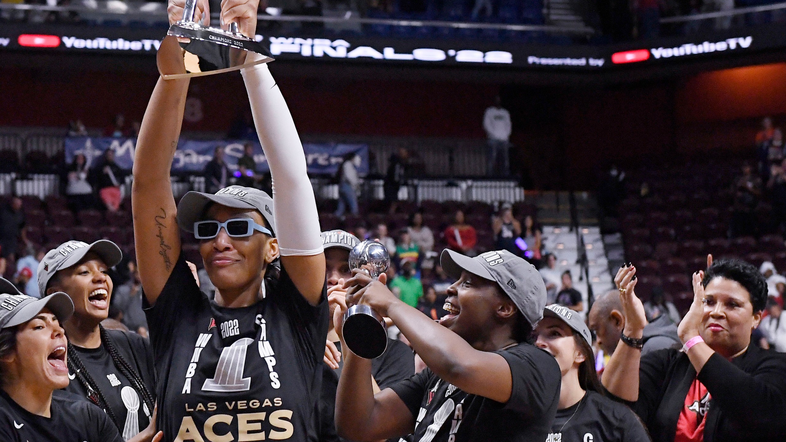 FILE - Las Vegas Aces' A'ja Wilson holds up the championship trophy as Natalie Williams, far right, looks on, during a celebration of the team's win in the WNBA basketball finals against the Connecticut Sun, Sept. 18, 2022, in Uncasville, Conn. (AP Photo/Jessica Hill, File)