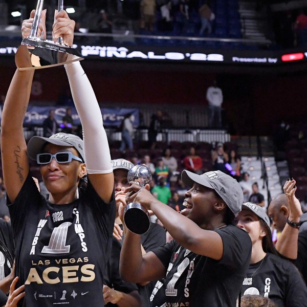 FILE - Las Vegas Aces' A'ja Wilson holds up the championship trophy as Natalie Williams, far right, looks on, during a celebration of the team's win in the WNBA basketball finals against the Connecticut Sun, Sept. 18, 2022, in Uncasville, Conn. (AP Photo/Jessica Hill, File)