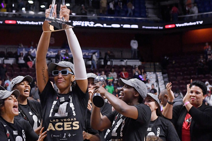 FILE - Las Vegas Aces' A'ja Wilson holds up the championship trophy as Natalie Williams, far right, looks on, during a celebration of the team's win in the WNBA basketball finals against the Connecticut Sun, Sept. 18, 2022, in Uncasville, Conn. (AP Photo/Jessica Hill, File)