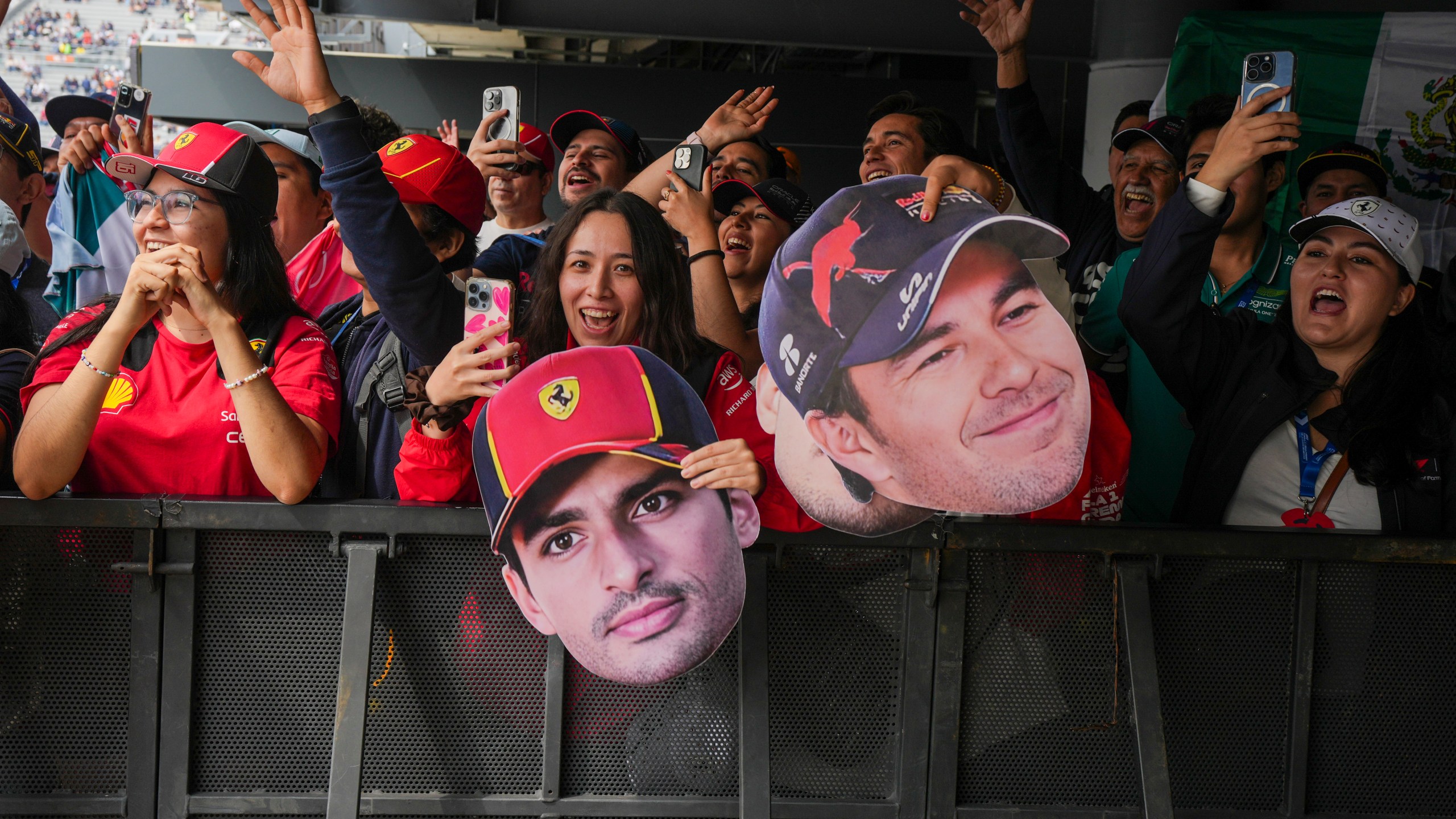 Fans hold cutouts of Ferrari driver Carlos Sainz, center, of Spain, and Red Bull driver Sergio Perez, of Mexico, during the third free practice one day ahead of the Formula One Mexico Grand Prix auto race at the Hermanos Rodriguez racetrack in Mexico City, Saturday, Oct. 26, 2024. (AP Photo/Fernando Llano)