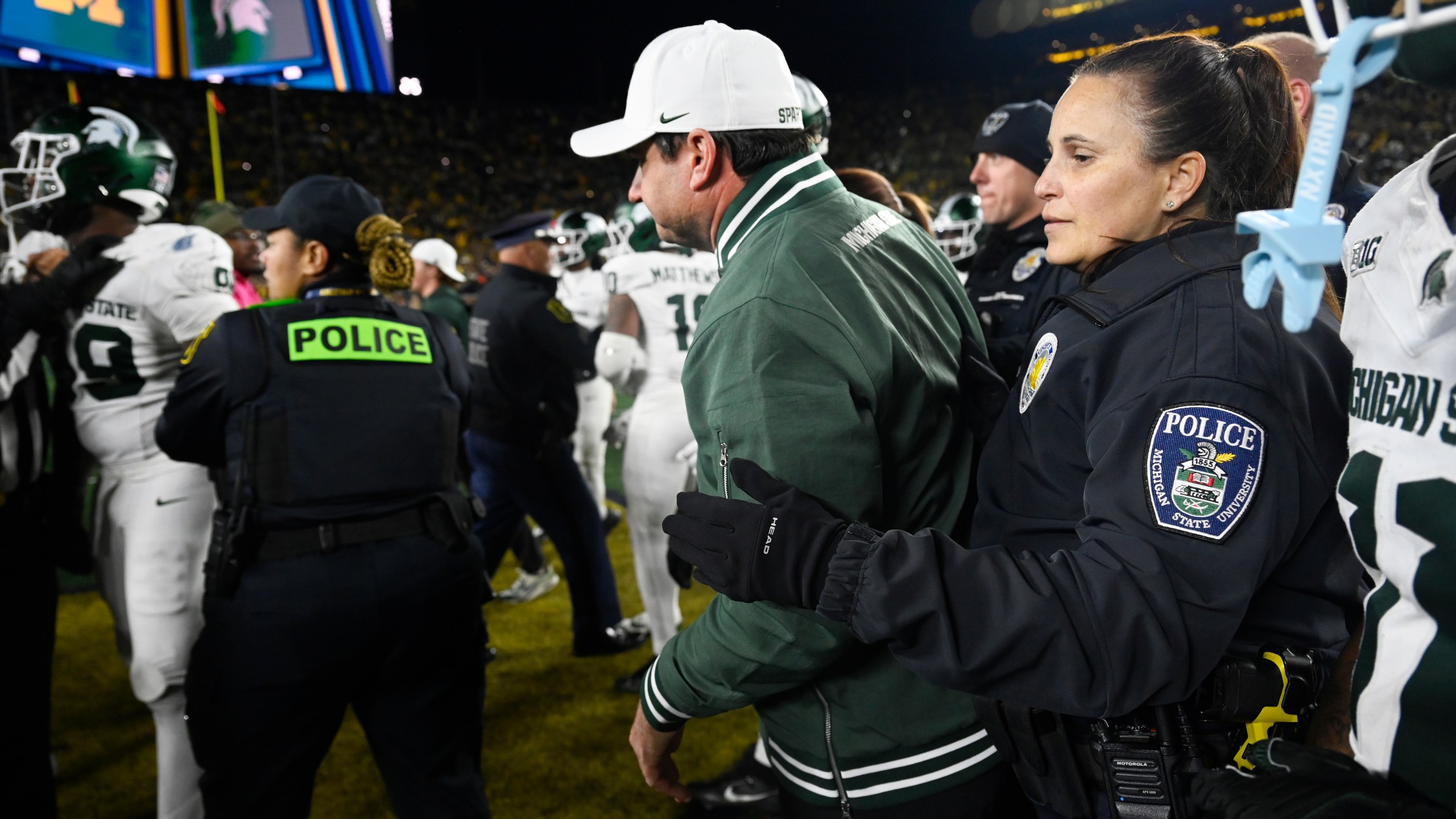 A Michigan State University policewoman holds back head coach Jonathan Smith from getting in the middle of a fight that broke out against Michigan following an NCAA college football game, Saturday, Oct. 26, 2024, in Ann Arbor, Mich. (AP Photo/Jose Juarez)