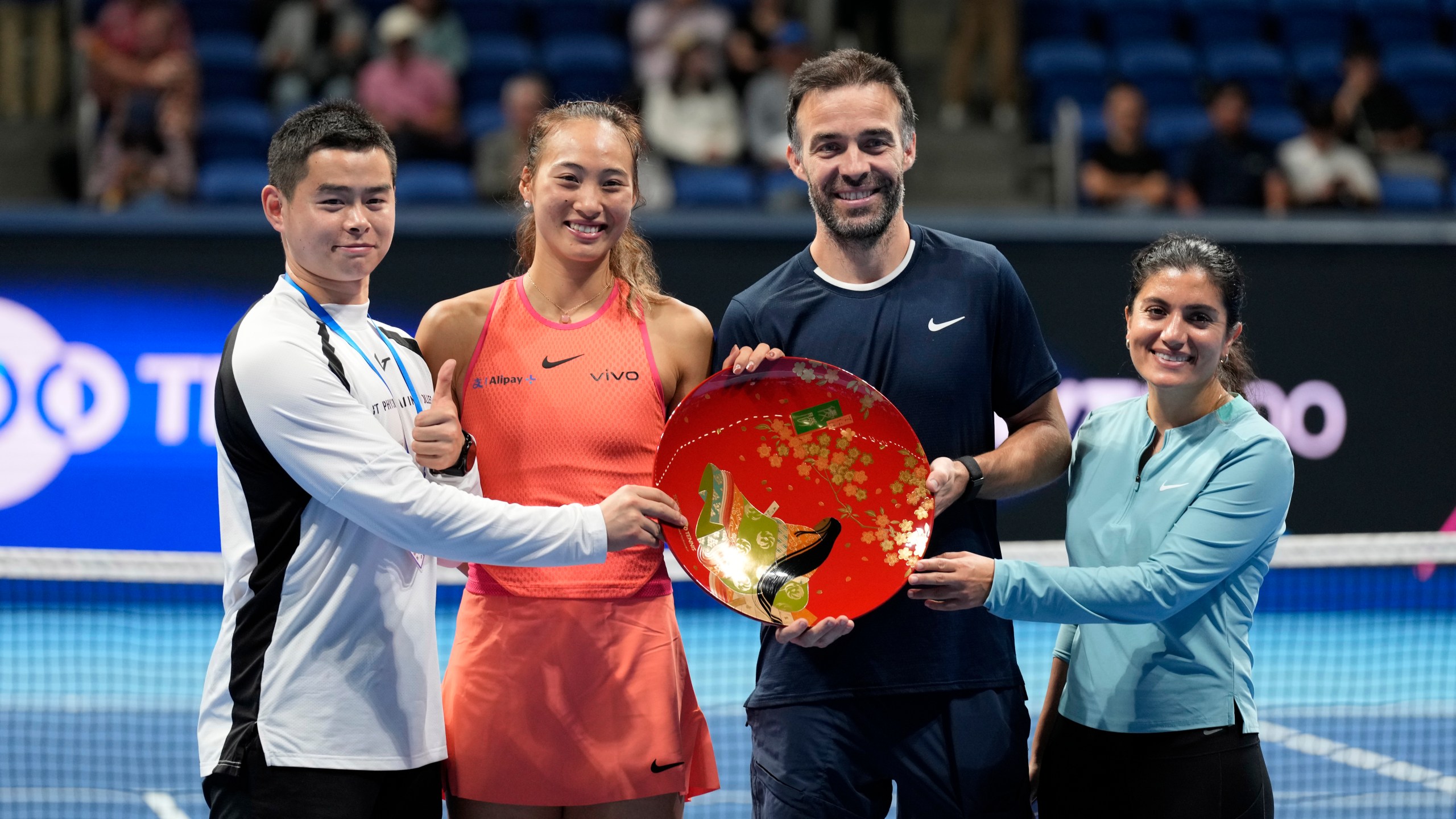 China's Zheng Qinwen and her supporting team pose with the trophy after she won the Pan Pacific Open women's tennis tournament at Ariake Coliseum, in Tokyo, Sunday, Oct. 27, 2024. (AP Photo/Eugene Hoshiko)