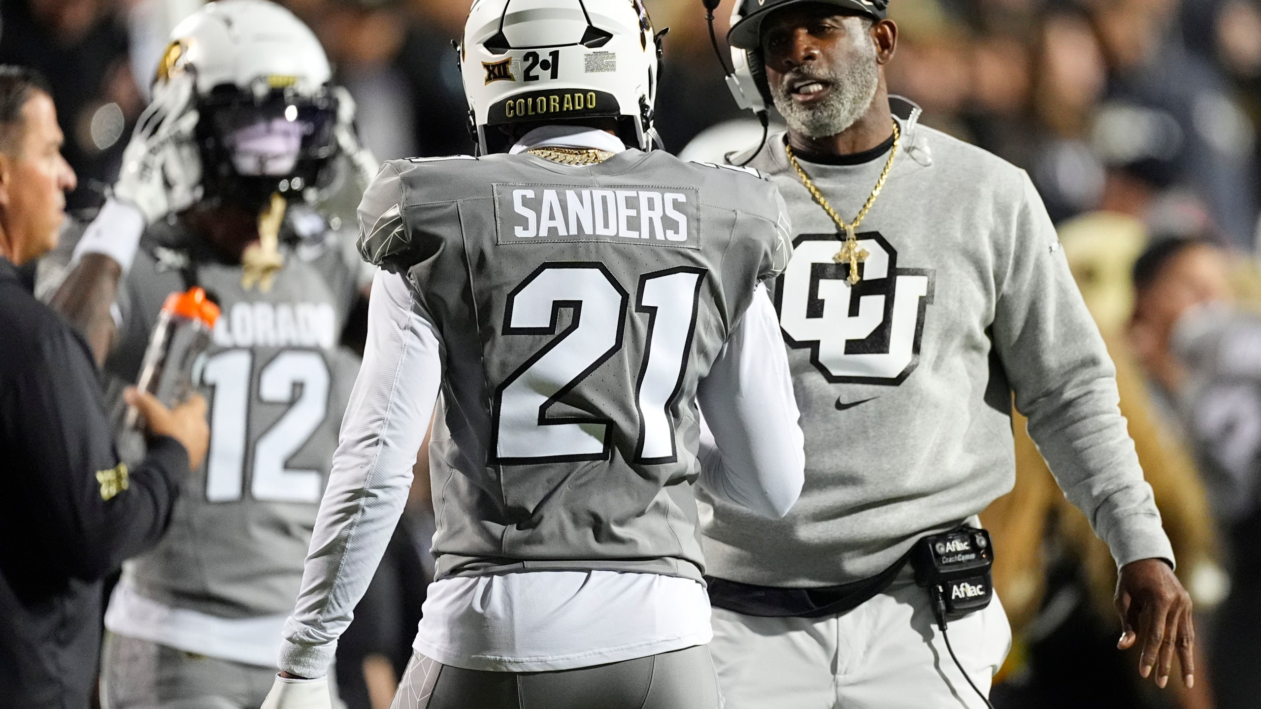 Colorado head coach Deion Sanders, right, confers with his son, safety Shilo Sanders (21), in the first half of an NCAA college football game against Cincinnati, Saturday, Oct. 26, 2024, in Boulder, Colo. (AP Photo/David Zalubowski)