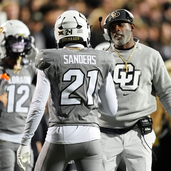 Colorado head coach Deion Sanders, right, confers with his son, safety Shilo Sanders (21), in the first half of an NCAA college football game against Cincinnati, Saturday, Oct. 26, 2024, in Boulder, Colo. (AP Photo/David Zalubowski)