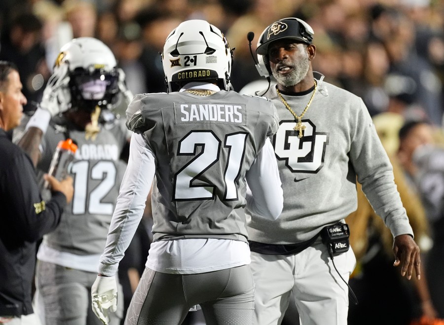 Colorado head coach Deion Sanders, right, confers with his son, safety Shilo Sanders (21), in the first half of an NCAA college football game against Cincinnati, Saturday, Oct. 26, 2024, in Boulder, Colo. (AP Photo/David Zalubowski)