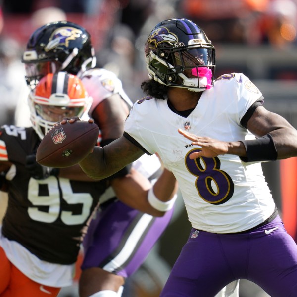 Baltimore Ravens quarterback Lamar Jackson (8) throws in from top Cleveland Browns defensive end Myles Garrett (95) during the first half of an NFL football game in Cleveland, Sunday, Oct. 27, 2024. (AP Photo/Sue Ogrocki)