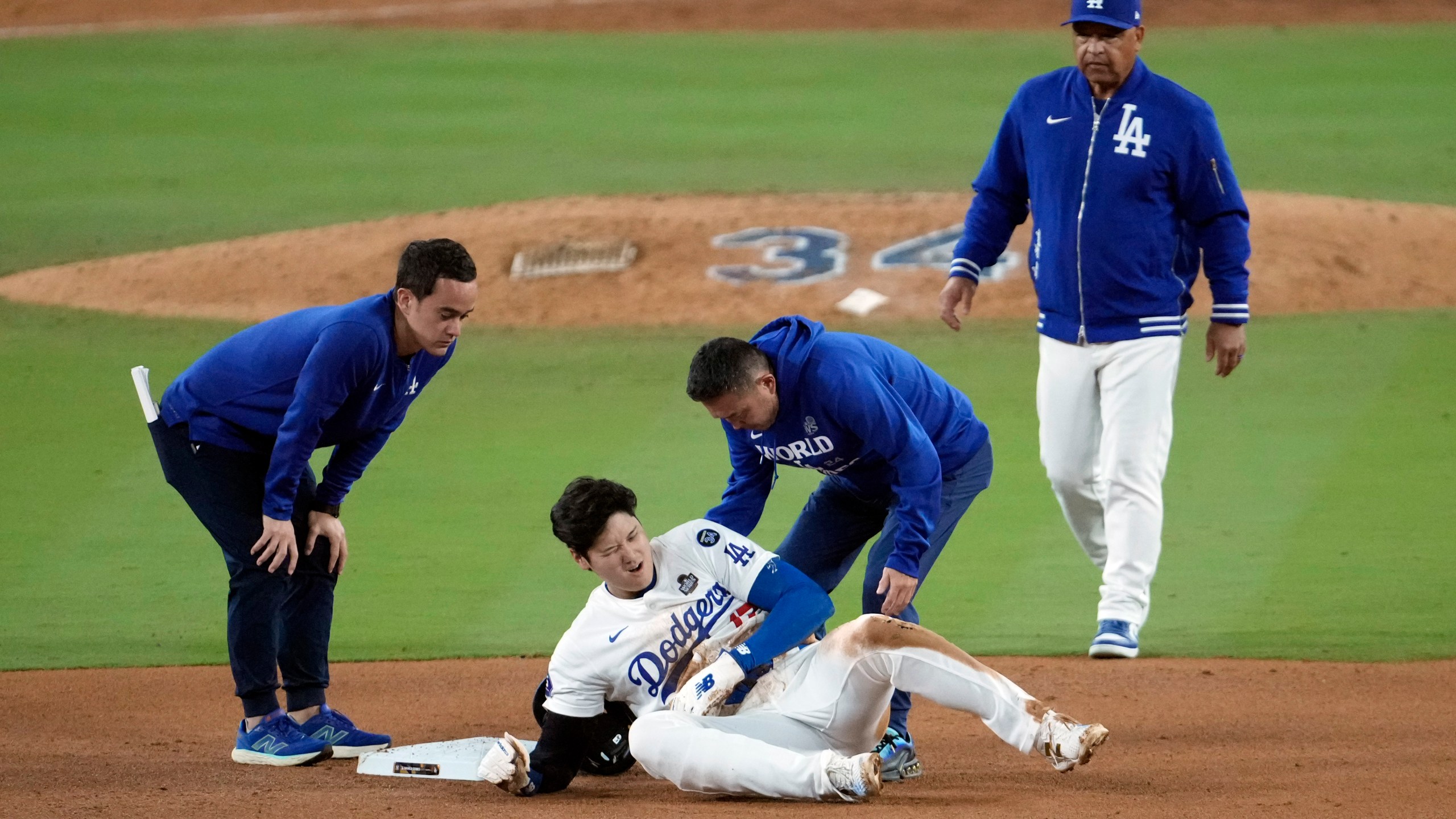 Los Angeles Dodgers' Shohei Ohtani, center, reacts after being injured while trying to steal second base against the New York Yankees during the seventh inning in Game 2 of the baseball World Series, Saturday, Oct. 26, 2024, in Los Angeles. (AP Photo/Julio Cortez)