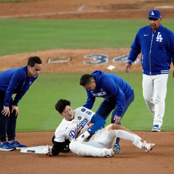 Los Angeles Dodgers' Shohei Ohtani, center, reacts after being injured while trying to steal second base against the New York Yankees during the seventh inning in Game 2 of the baseball World Series, Saturday, Oct. 26, 2024, in Los Angeles. (AP Photo/Julio Cortez)